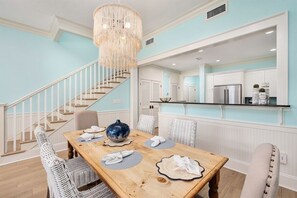 Een eetgedeelte met een houten tafel, witte stoelen en een kroonluchter.