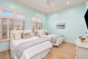 Camera da letto con due letti, una ventola a soffitto e un quadro appeso al muro.