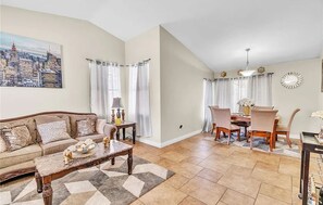 A living room with a sofa, coffee table, and dining area with chairs and a table. - 3-bedroom house in charming North Las Vegas with AC (North Las Vegas)