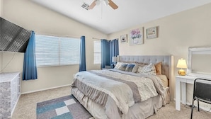 A bedroom with a bed, a desk, a chair, a ceiling fan, and a window with curtains. - 3-bedroom house in charming North Las Vegas with AC (North Las Vegas)