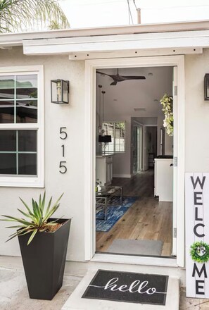 A modern house with a number '515' on the wall, a 'hello' mat, and a 'WELCOME' sign.