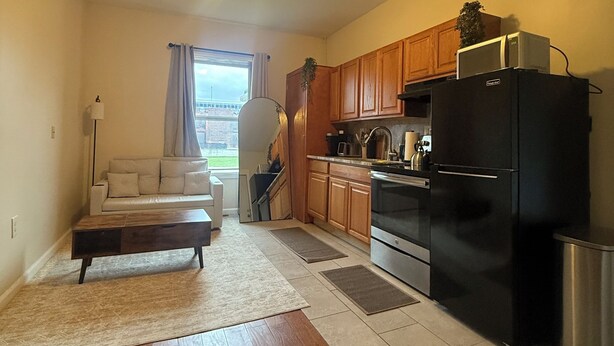 A compact living space with a kitchenette, a sofa, a coffee table, and a view of the outdoors. - Pet friendly 1Bd In Arena District With Event Parking (Detroit)