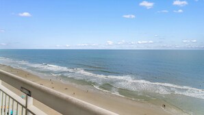 A beach with a 'No Smoking' sign, clear skies, and waves approaching the shore.