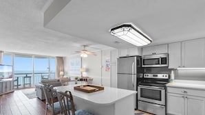 A modern kitchen with white cabinets, stainless steel appliances, and a large island.