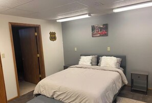A bedroom with a bed, a nightstand, a door, and a wall-mounted picture. - Hunters and Anglers welcomed (Palisade)