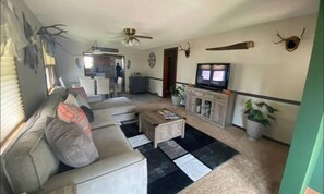 Una sala de estar con un sofá, una mesa de centro, televisión y adornos de cornamenta.