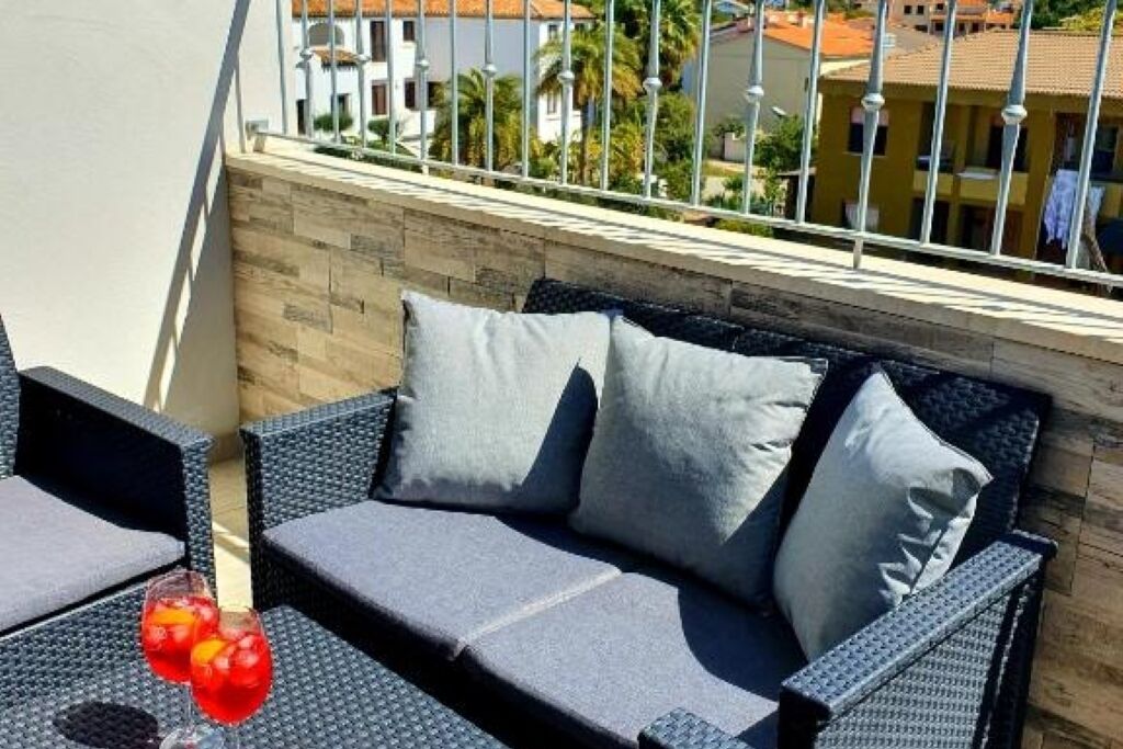 A balcony with wicker furniture and a drink.