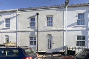 A white two-story building with a white door and windows, a satellite dish, and a street lamp. - Spacious 3-Bed Period Home Near Bath Road (Cheltenham)