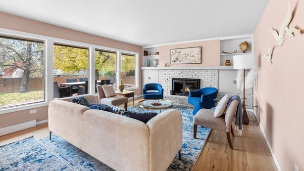 A modern living room with a fireplace, large windows, and a cozy seating area. - Stylish South Hill Getaway | Bar & Game Room (Spokane)