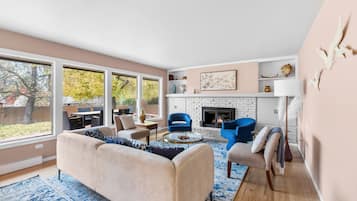 Un salon moderne doté d’une cheminée, de grandes fenêtres et d’un coin salon confortable.