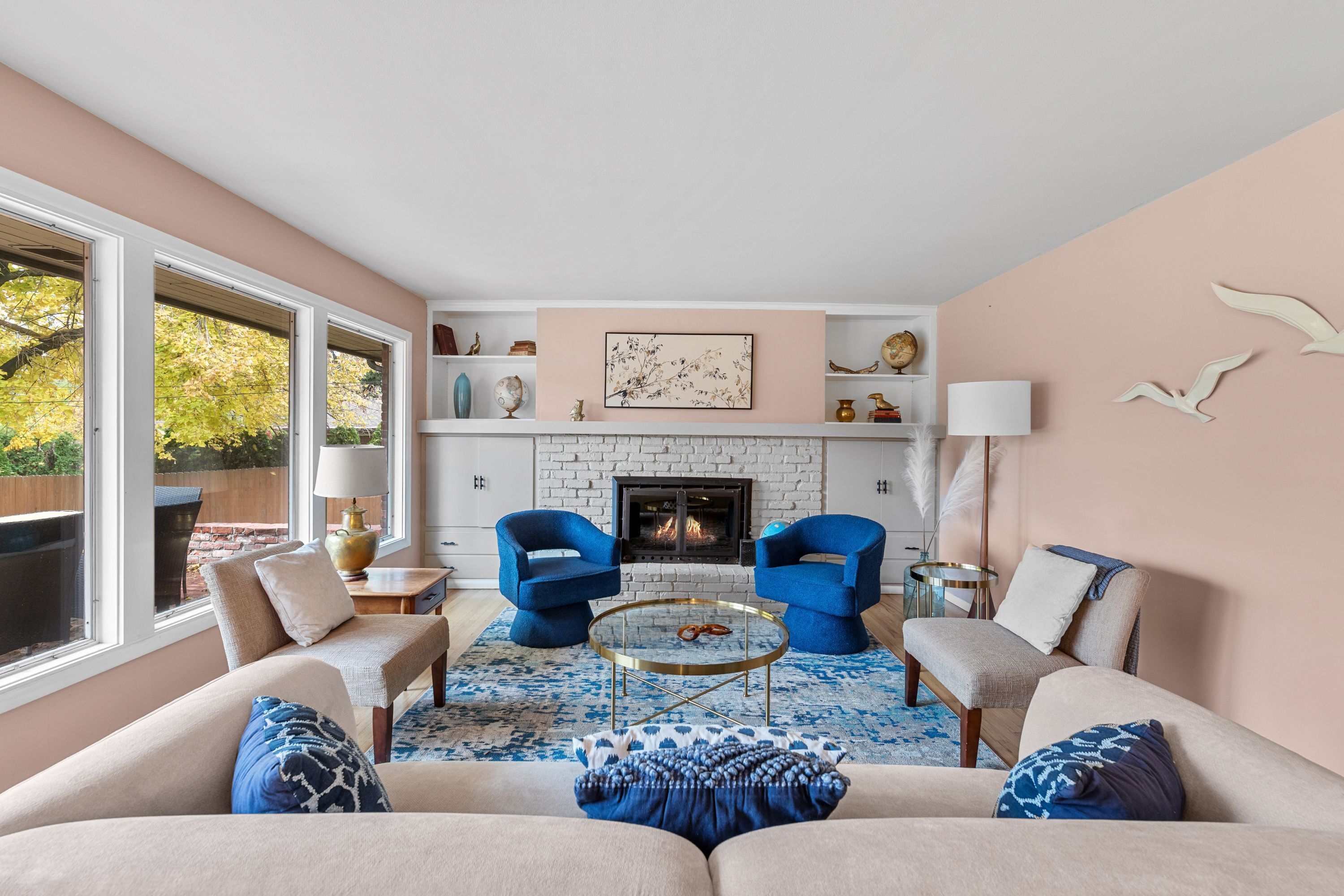 A living room with a fireplace, two blue armchairs, a beige sofa, and a coffee table.