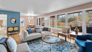 A spacious living room with a beige sofa, blue and white patterned rug, and a glass coffee table. - Stylish South Hill Getaway | Bar & Game Room (Spokane)