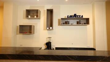 A reception area with a marble counter, a coffee machine, and shelves with branded items.