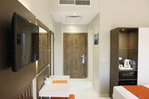 A hotel room with a TV, a wooden door, a white desk, and a bed. - Gloria Aqua Park (Aswan)