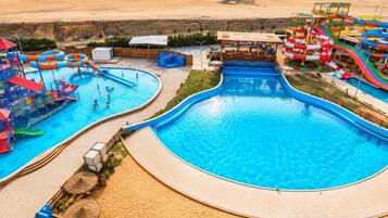 Una gran piscina con múltiples toboganes de agua y una zona de juegos separada para niños.
