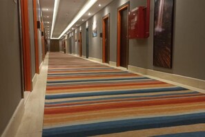 A hotel corridor with a striped carpet, doors, and wall-mounted signs. - Gloria Aqua Park (Aswan)