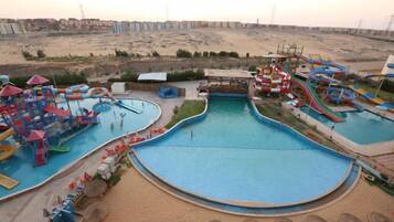 A water park with multiple pools and slides, surrounded by a sandy landscape.