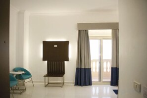 A hotel room with a large window, a flat-screen TV, and a seating area with chairs. - Gloria Aqua Park (Aswan)