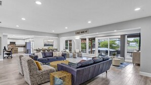 A spacious living area with a large sofa, a dining table, and a kitchen in the background.