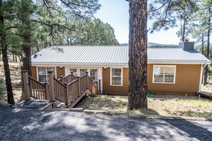 A two-story cabin with a metal roof, wooden deck, and a small porch. - Rustic cabin in charming Ruidoso (Ruidoso)