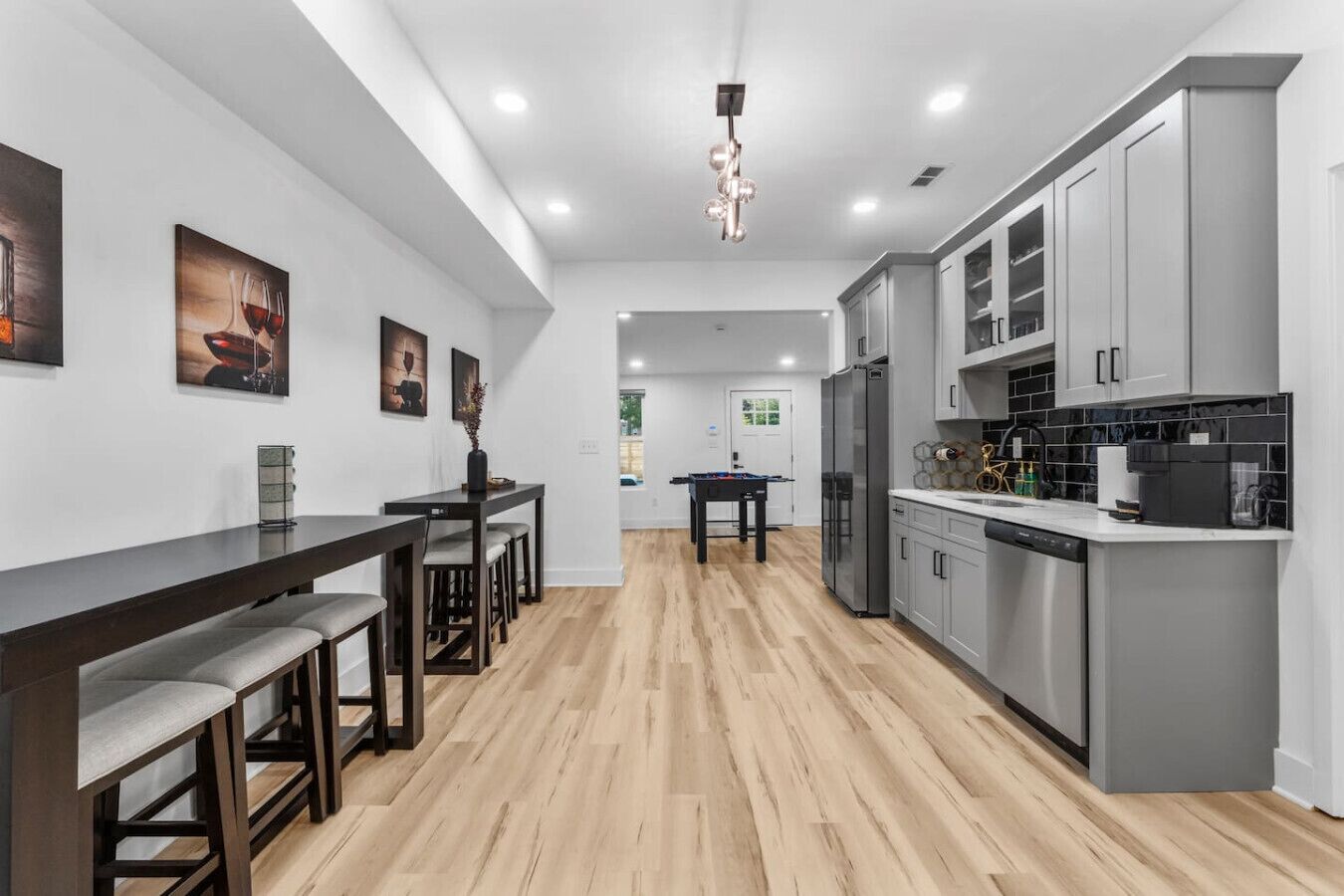 Una cocina moderna con armarios grises, una mesa de comedor de madera y una barra.
