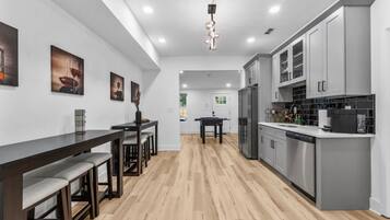 Una cocina moderna con armarios grises, una mesa de comedor de madera y una barra.