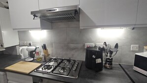 A modern kitchen with a gas stove, a coffee maker, and a range hood.