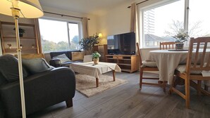 A living room with a sofa, TV, table, and chairs.