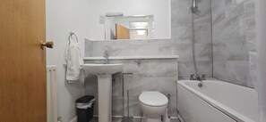 A bathroom with a pedestal sink, toilet, and bathtub. - Chiswick Residence (London)