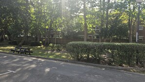A park with a paved path, benches, and neatly trimmed bushes.
