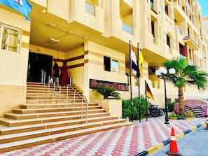 A hotel entrance with a staircase leading to the lobby, multiple flags, and a palm tree. - Florenze Khamsin Hurghada J-113 (Hurghada)