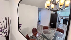 Un intérieur moderne avec un coin repas, une cuisine à l’arrière-plan et un grand miroir qui reflète l’espace.