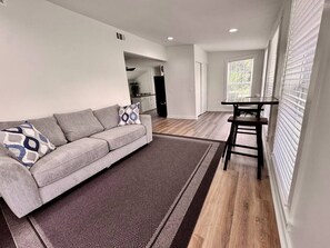 A modern living room with a grey sofa, patterned rug, and a small table.