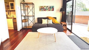 A modern living room with a sofa, a coffee table, and a bookshelf. - The Palm Tree Loft, close to shops and lake (Green Point)