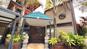 A modern building with a covered entrance, a staircase, and a variety of plants. - The Palm Tree Loft, close to shops and lake (Green Point)