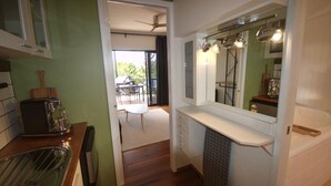 A kitchen with a built-in oven, a coffee maker, and a dining area with a table and chairs. - The Palm Tree Loft, close to shops and lake (Green Point)