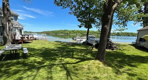 A lakeside property with a dock, picnic tables, and boats.