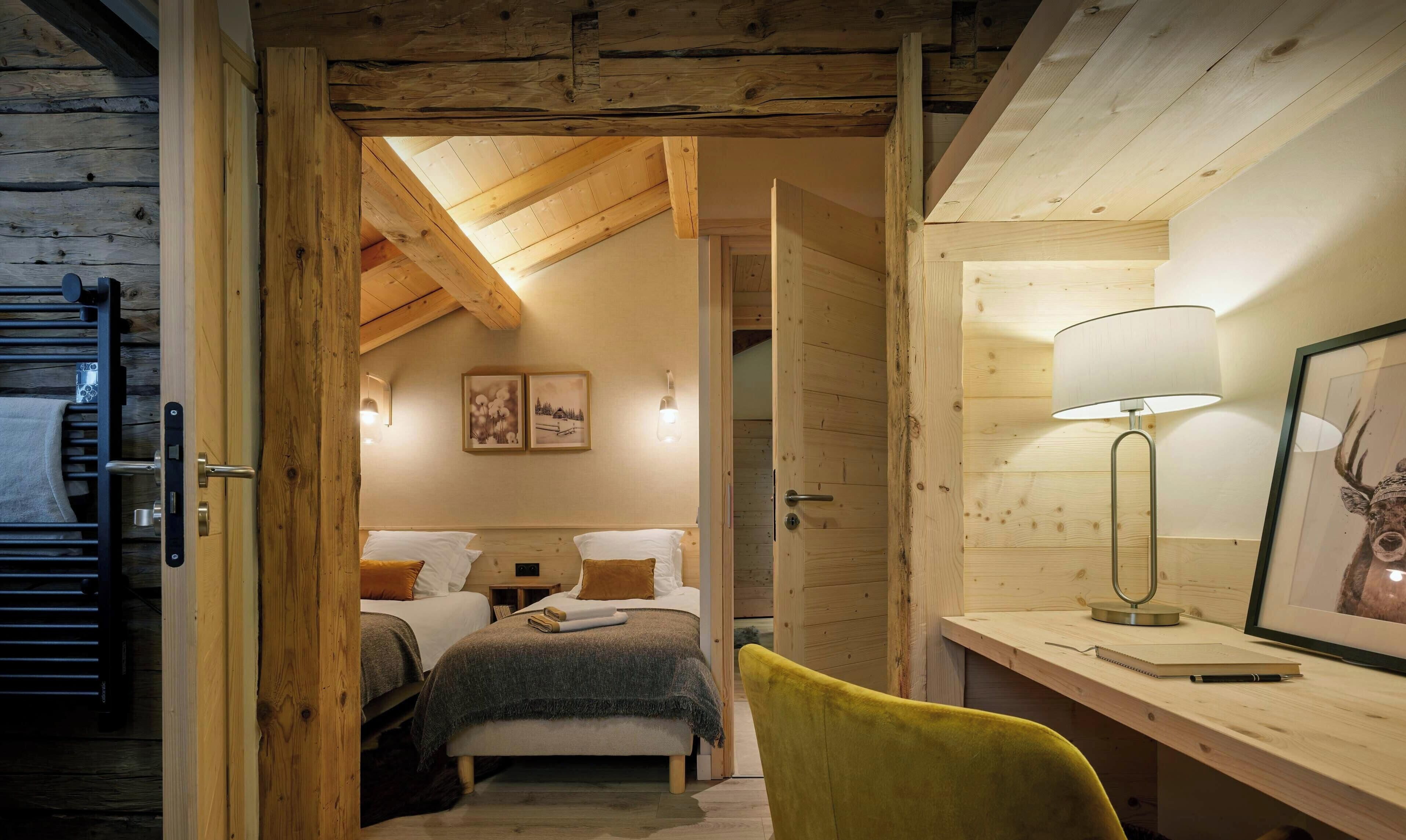 L’intérieur d’un chalet en bois comprend un espace de couchage en mezzanine, un bureau avec une lampe et des œuvres d’art encadrées.