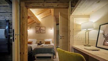 L’intérieur d’un chalet en bois comprend un espace de couchage en mezzanine, un bureau avec une lampe et des œuvres d’art encadrées.