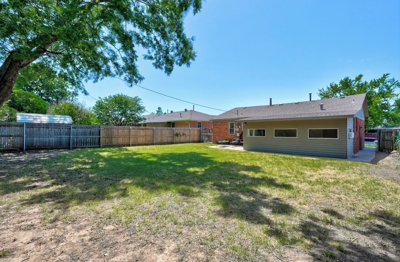 A single-story house with a fenced backyard, a covered patio, and a small attached garage.