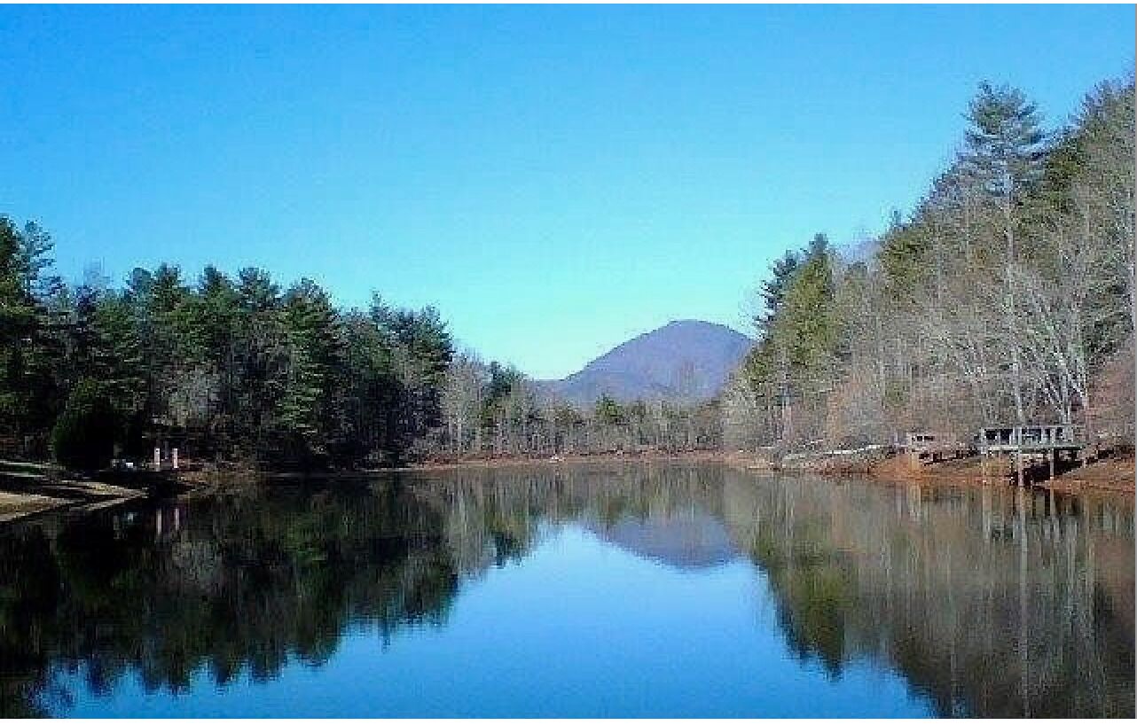 A calm lake with a mountain in the background and trees on both sides.