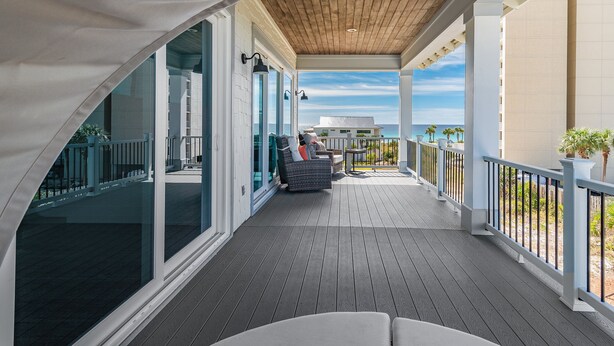 A covered outdoor deck with a wooden ceiling, glass doors, and a view of the ocean. - 6 Bedrooms | 6.5 Bathrooms | Sleeps 22 (Miramar Beach)