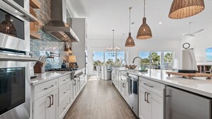 A modern kitchen with white cabinetry, stainless steel appliances, and a view to the outdoors. - 6 Bedrooms | 6.5 Bathrooms | Sleeps 22 (Miramar Beach)
