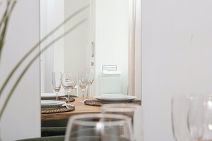 Uma área de refeições com uma mesa posta para quatro pessoas, incluindo copos de vinho e pratos.