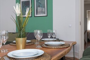 A dining table set with plates, glasses, and a plant in a gold pot.