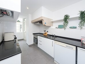 A modern kitchen with white cabinets, a black countertop, a built-in oven, and a dishwasher.