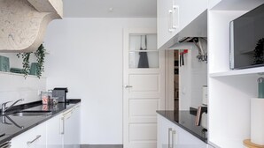 A modern kitchen with white cabinets, a black countertop, and a stainless steel sink.