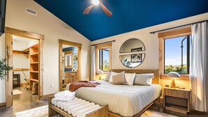 A bedroom with a large bed, bedside tables, a ceiling fan, and a view of the outdoors. - 360Mtn Views, OutdoorTheatre, Hottub, Sauna, GmRm (Asheville)