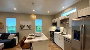 A modern kitchen with a central island, stainless steel appliances, and a dining area with a sofa and chairs.