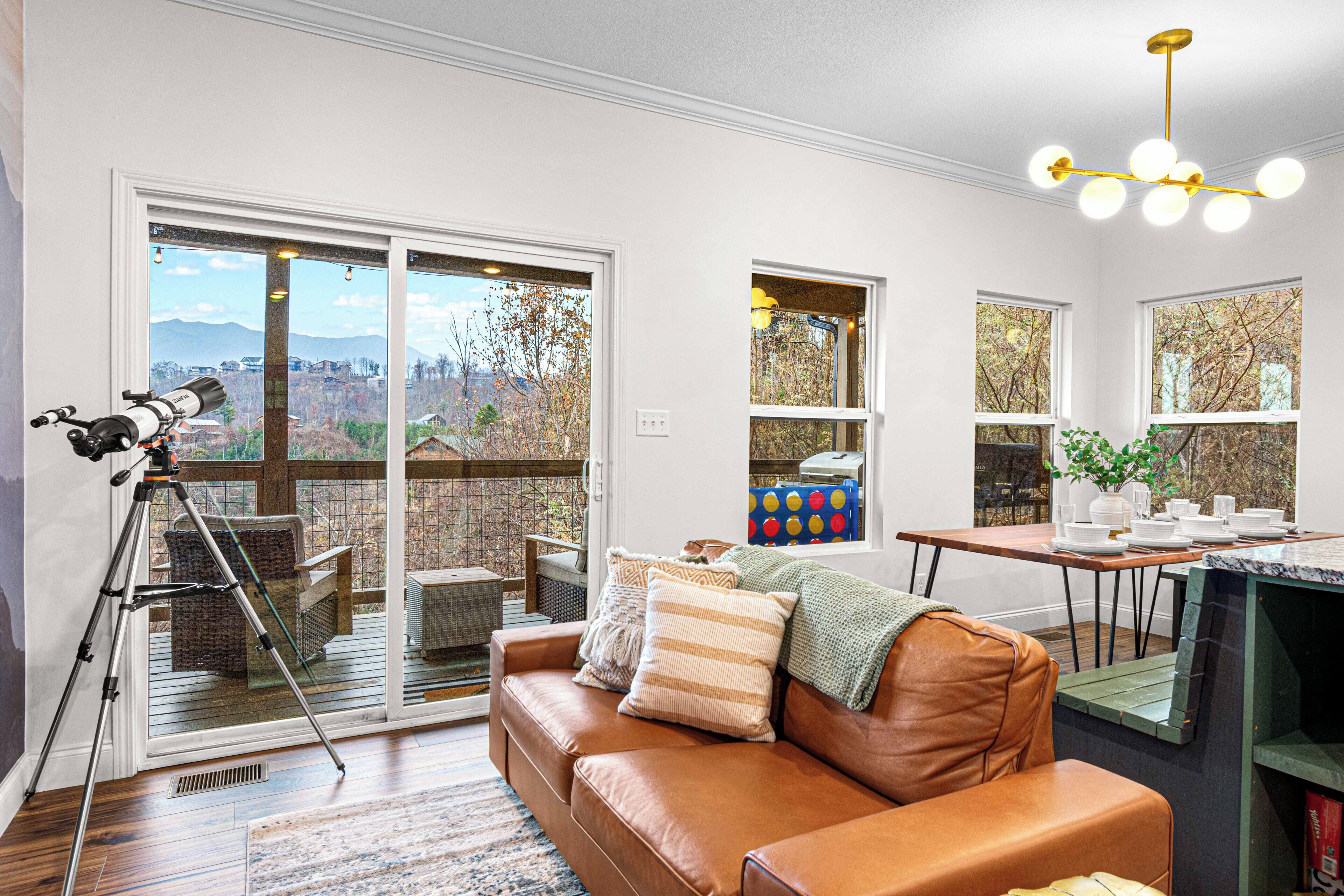 A living room with a leather sofa, a dining table, and a telescope.